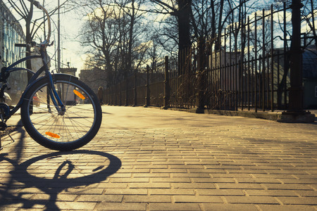 Bike with orange reflector at the fence of the park in the early spring on a sunny dayの写真素材