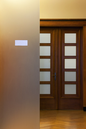 Wooden door with glass and plate in a respectable office with parquet floorの写真素材