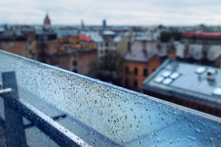 The roofs of the city from the top of the glass partition with raindrops and the horizonの写真素材