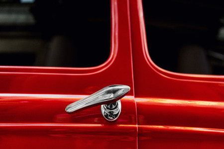 Silver door handles vintage red car with reflection in the windows of the old townの写真素材