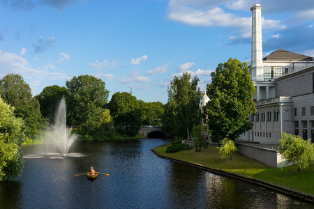 People relax on a boat on a canal in the town near the Opera and Ballet Theatre in Rigaの写真素材