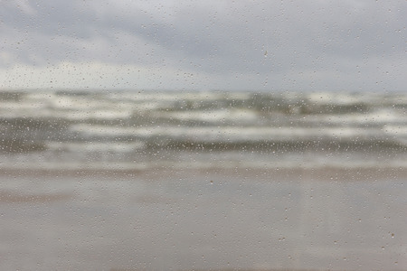 The storm with waves and horizon in the Baltic Sea through the raindrops on the glassの写真素材