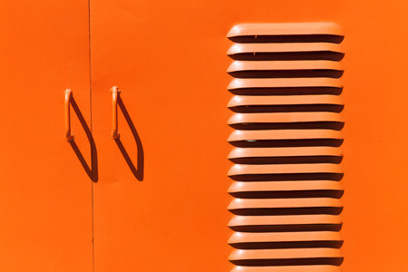 Iron orange colored door handles and shadows with ventilation slotsの写真素材