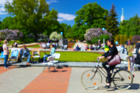 Tourists in bright robes walking in the center of Riga among the flowers along the street cafe in park. Blurryの写真素材