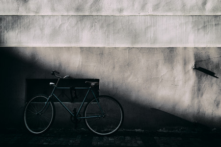 Bike stands in the shadow of the old wall with a sloping terrain with a beautiful lightの写真素材