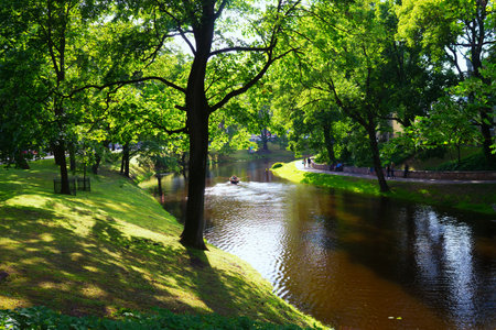 Latvia, Riga. July 2015. Tourists walk and ride on a boat on the canal in the city park in the summer in Rigaのeditorial素材