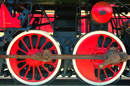 Latvia, Riga. July 2015. Red locomotive wheel with black iron machinery parts
