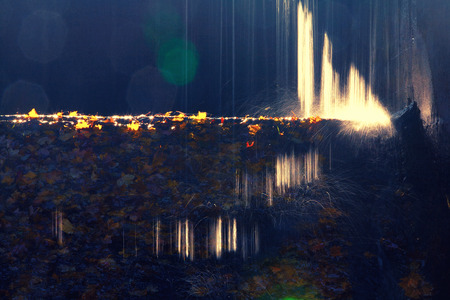 Water with patches of light falls on a stream of yellow leaves in autumnの写真素材