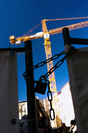 Latvia, Riga. Lock and chain on the gate building on a background of yellow crane and a bright blue...