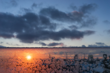 Orange Sunset with clouds on the blue sky through the frosted glass with the silhouette of the evening cityの写真素材