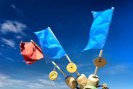 Red and blue flags on floats fishing nets on the shore of the Baltic Sea on a sunny summer day against the blue sky with cloudsの写真素材