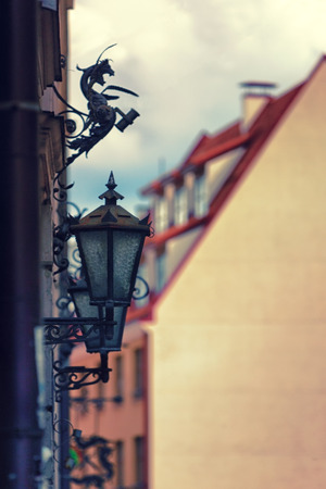 Antique lanterns and openwork holder for flags on the wall of a house in Old Riga in Latviaの写真素材