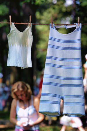 Vintage underwear drying on the rope with wooden clothespins on a background of green trees and girlの写真素材