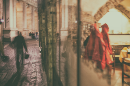 Evening life on the streets and cafes with tables and a hanger behind the glass in Italyの写真素材