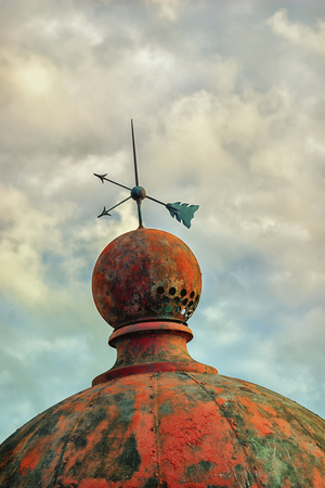 Dome of an old lighthouse behind a wooden fence near the Baltic Sea in the dunes against the background of a cloudy summer skyの写真素材