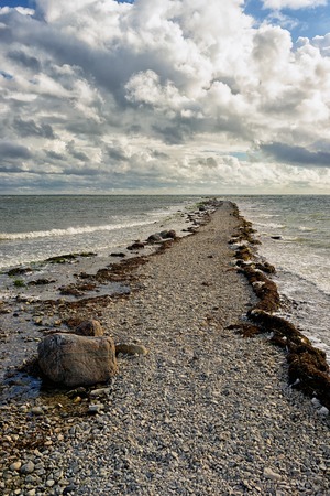 A narrow road to the horizon of stones in the middle of the Baltic Sea on a sunny day with beautiful...