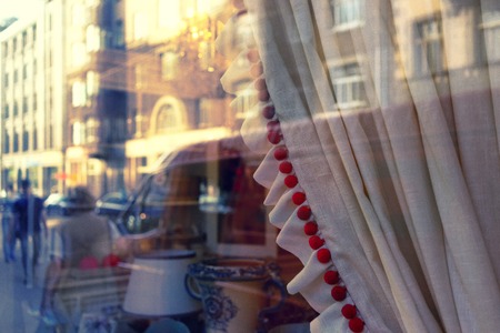 Buildings of the old city of Riga are reflected in the shop window with curtains and flags with toysの写真素材