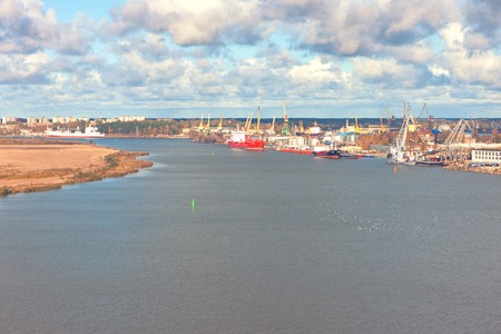 Port with cranes on the river Daugava in the capital of Latvia city of Riga against the background of a summer cloud with cloudsの写真素材