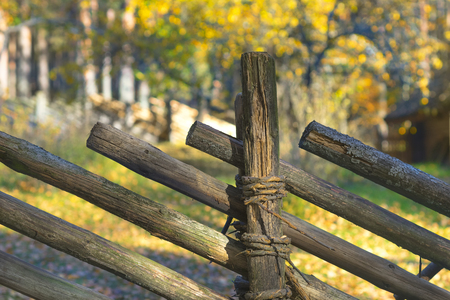 A fence of tilted wooden beams against the background of the autumn forestの写真素材