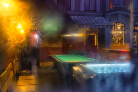 The evening old city is reflected in the window of the restaurant with billiards and table football...