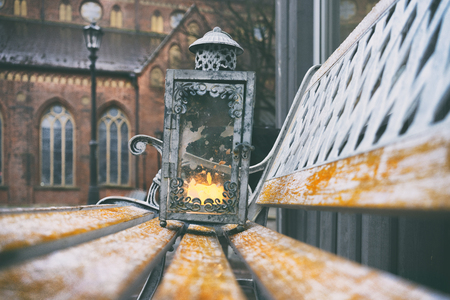 Vintage lantern with a burning wax candle on a bench on Dome Square in the ancient city of Rigaの写真素材