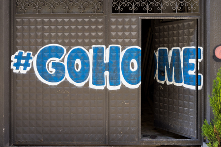Graffiti on the iron gate with Hashtag Go Home with the door open. Istambulの写真素材