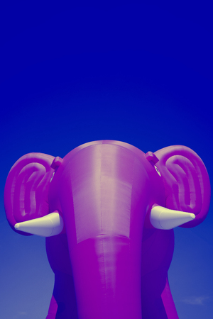 Pink big inflatable elephant with white tusks on a blue sky backgroundの写真素材