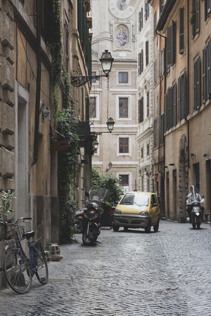 Different transport on the narrow street of Rome with lanterns and ancient buildingsの写真素材