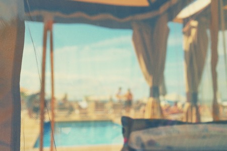 Closed beach by the sea with a swimming pool a place of rest on a sunny summer day through a perforated curtain. Blurryの写真素材