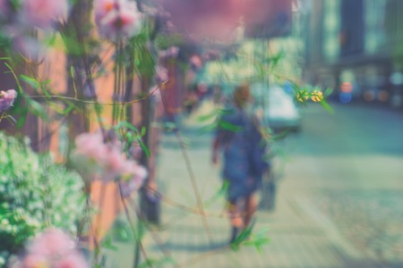The girl walks along the sidewalk along the street against the background of decorative flowers and...