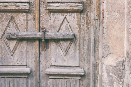 The old door with the iron handle is closed with a board with nailsの写真素材