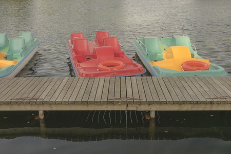 Water colored bicycles with pedals and lifebuoys moored at a wooden bridge on a lake