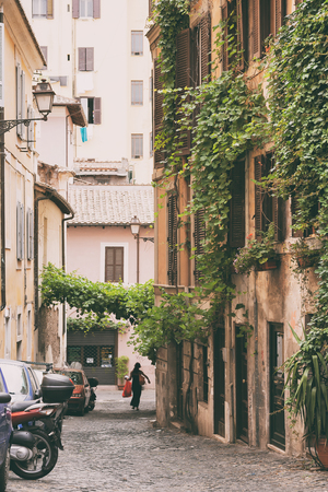 A girl in a black dress goes shopping in an ancient street in the center of Rome in the summerの写真素材