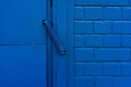 Metal spring on the doors and a blue brick wall