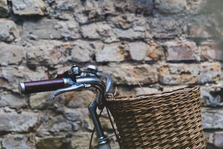 Vintage bicycle with leather handles and steel bell with wicker basket on the background of an old brick wallの写真素材