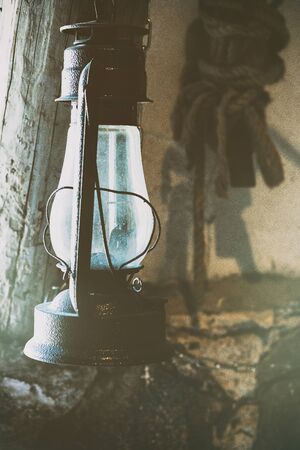 Vintage kerosene lamp in the shed on the background of the wall with a ropeの写真素材