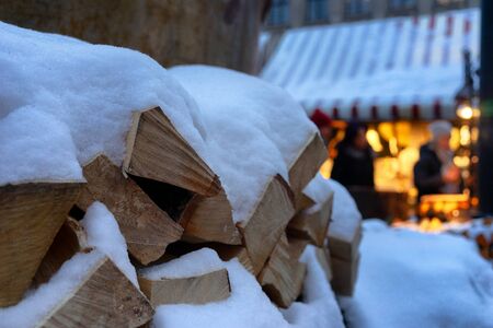 Firewood for a fireplace lies under snow on a city street against the background of the Christmas Yarmakiの写真素材