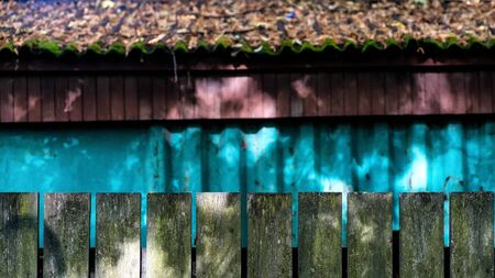 Bright colors of a wooden fence on a background of a wall and a roof with yellow leavesの写真素材