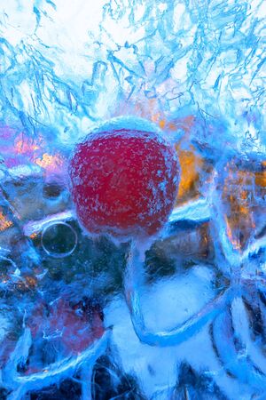 Frozen fresh apples in an array of ice on a background of Christmas market lightsの写真素材