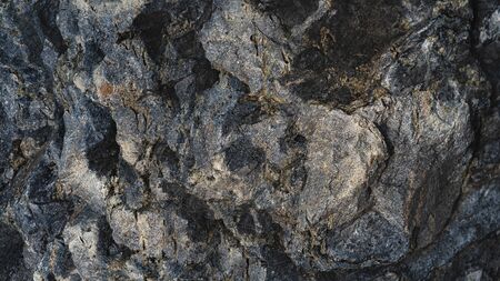 Relief deep texture of a large dark stone as a background of stability and strength