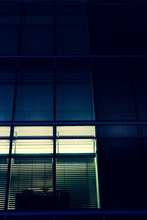 Blue urban facade and a table with red flowers behind the blinds in the office. Berlin. Germany