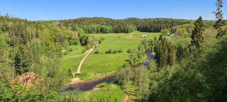 River Valley in Gauja National Park. People walk on the field against the background of the forest. Ligatneの写真素材