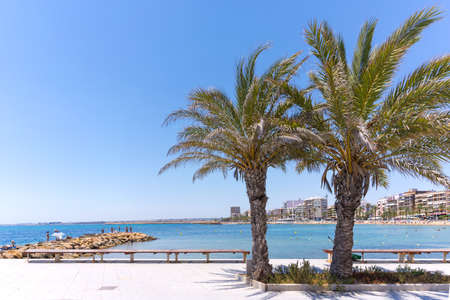 Embankment of the southern resort town in summer in Spain. People swim in the Mediterranean Sea on a hot day.の写真素材