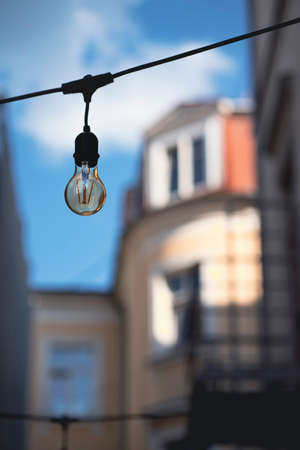 Light bulb on a wire in the cityの写真素材
