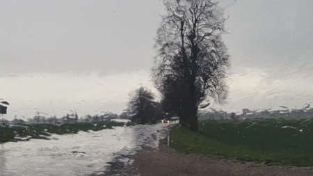 Blurred outlines of cars and trees on a road through glass with raindrops outside the city. Latviaの写真素材