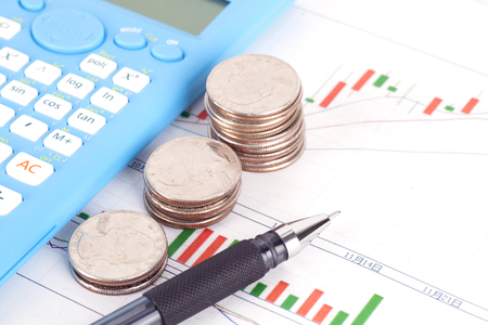 Financial investment plan with a pen, coins and calculatorの写真素材