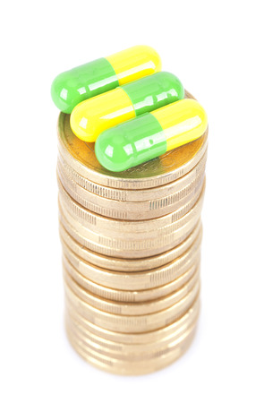 Capsules on a stack of coins on white backgroundの写真素材