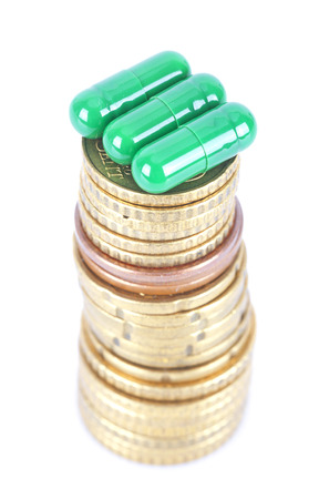 Capsules on a stack of coins on white backgroundの写真素材