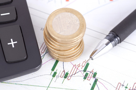 Financial investments concept with a pen, coin stacks and calculatorの写真素材