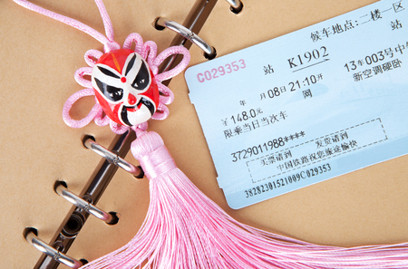 Train tickets on a brown notebook page with a Chinese traditional knotのeditorial素材